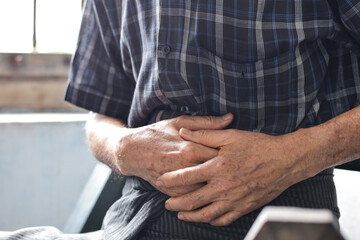 Asian man suffering from abdominal pain. It can be caused by stomach ache, enteritis, colitis, appendicitis, hepatitis, pancreatitis, food poisoning, etc.