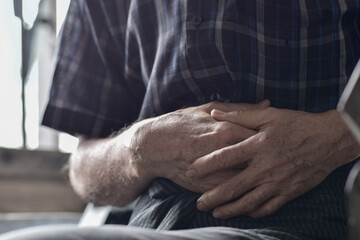 Asian man suffering from abdominal pain. It can be caused by stomach ache, enteritis, colitis, appendicitis, hepatitis, pancreatitis, food poisoning, etc.