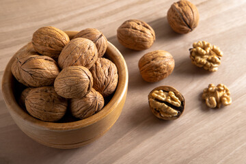 Bowl of walnuts and whole walnut kernels on wooden background,top view