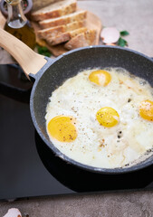 Fried Egg in cast iron frying pan on black induction hob
