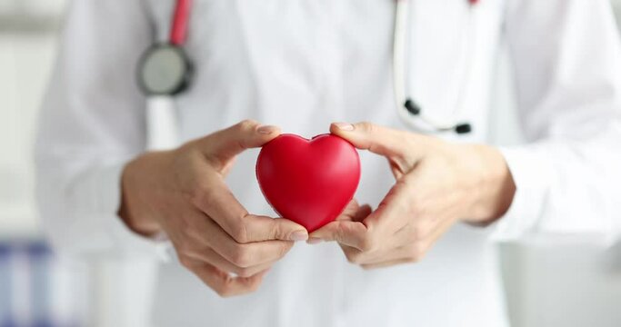 Doctor holding red toy heart in his hands closeup 4k movie slow motion