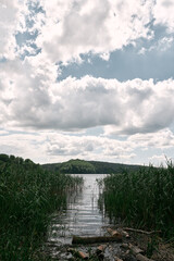 Fototapeta premium View from the coast of the lake. Beautiful landscape with calm lake and bright trees at sunset. Bright summer day scene.