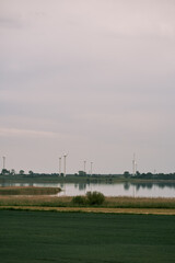 Distant windmill farm in the green fields. Wind turbines generating green and renewable energy