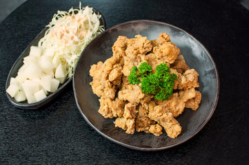 Korean Fried Chicken Original Gangjung, traditional Korean confectionery crackers on grill plate with pickle dishes on black table background