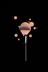 Professional brush with black handle for make up with drops of beige foundation, bb cream isolated on black