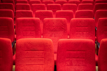 Fototapeta premium Cinema movie theater background. Red cozy cinema seats in empty theater. Armchairs with comfortable elbows.