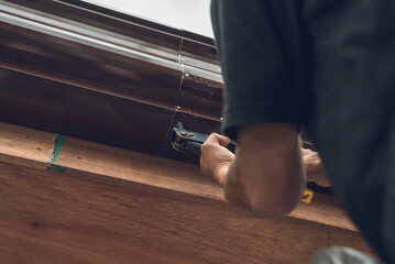 A handy man uses a pop rivet gun to fasten two pieces of a steel gutter together. Roof construction...