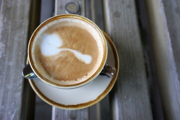 Tasse Cappuccino auf Naturholzbank bei Sonne am Nachmittag im Sommer 