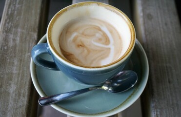 Blaue Tasse Cappuccino auf grauer Lattenholzfläche 