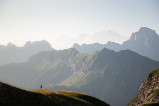  Man silhouette staring at the vastness of the mountains surrounding him. Mont Blanc mountains at sunrise in French Alps from the Lake of Peyre.
