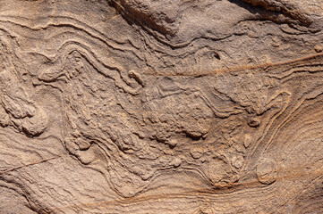 Stone wall is sand colored with various patterns and spots. Textured stone background of sand color with wavy patterns.