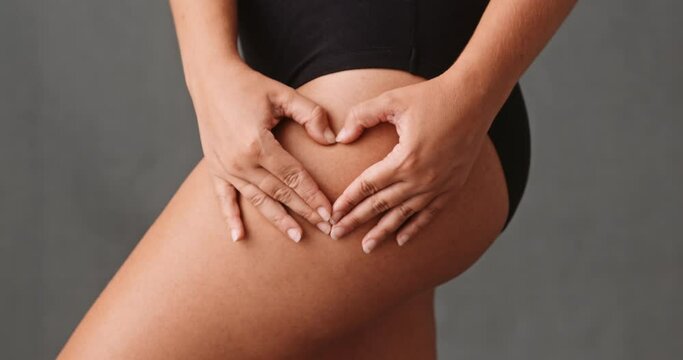 Young Caucasian woman making a heart shape on her thigh