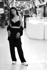 Young slender woman standing in a hall of a mall in black and white