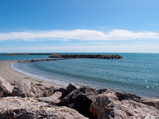 View of an empty sandy beach with rocks and stones under the blue sky