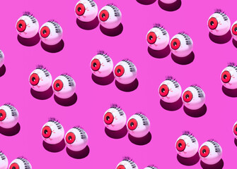 Funny eye balls creative pattern on neon pink background. Minimal Halloween concept.