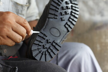 Loose leather shoe soles are being reattached with strong glue. Isolated on a shoe repairman...