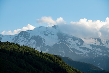 Clouds over the mountains. Amazing high rocks in the fog with green hills .