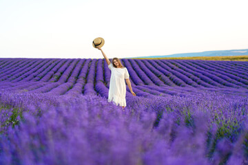 Young woman in a white dress walking in a lavender field