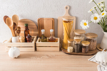 front view of the kitchen wooden countertop with various kitchen utensils, cans with various dry products. storage concept, eco kitchen interior.