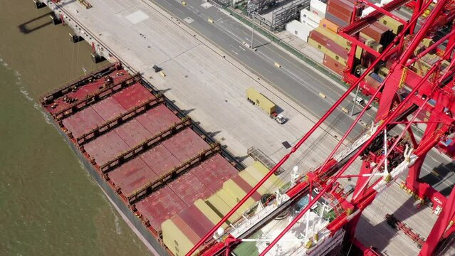 Large Cargo Ship Unloading With Large Red Cranes At Liverpool Docks. Drone Shot From Water Side With Cinematic Movement.