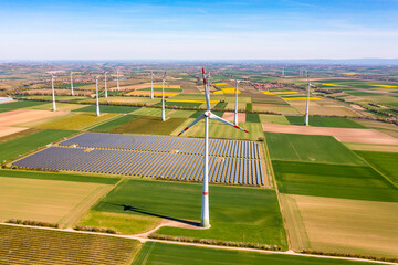 Panorama von Solarmodulen eines Solarparks als Freiflächenanlage inmitten von Windrädern zwischen...