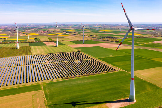 Luftaufnahme von riesigen Windr&auml;der zwischen Agrarfl&auml;chen und einem Solarpark im l&auml;ndlichen Gebiet, Deutschland