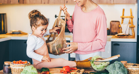 Woman having fun with her daughter while preparing food in the kitchen. - obrazy, fototapety, plakaty