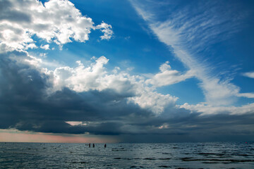 Rainy dark clouds during at sunset at Baltic sea. Dark sea water and heavy beautiful grey clouds in...