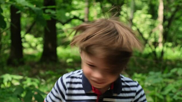 Little boy shakes his head in different directions and rubs his hair. Front view