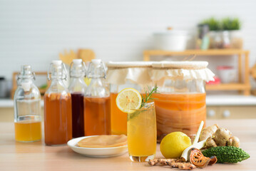 Kombu tea in a glass with ice, lemon slices and rosemary leaves, Homemade fermented raw kombucha tea in glass and bottles mix with fruit juice, scoby and herb on table.Healthy natural probiotic drink.