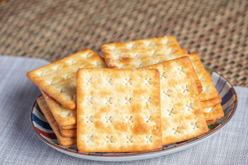 A pile of dry, thin crackers in a cup. Natural light.