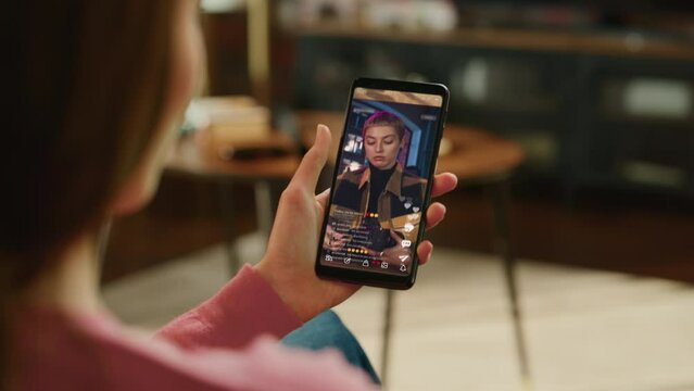 Person Using Social Media App on Smartphone, Looking at Live Stream Videos. Realistic Feed Scrolling on Mock-up Application Posts: Creativity, Dancing, Meme, Lifestyle, Device Review, Viral Content