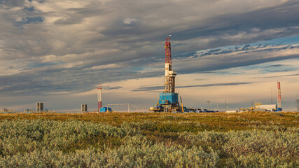 The summer landscape of the Arctic tundra against the background of infrastructure for drilling...