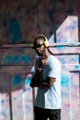 Fototapeta premium black guy with headphones with multicolored wall in the back