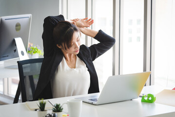 Business Asian woman working and stretch her body to relax herself from stress.