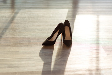 Black women's pumps with stiletto heels on a wooden floor. women's shoes