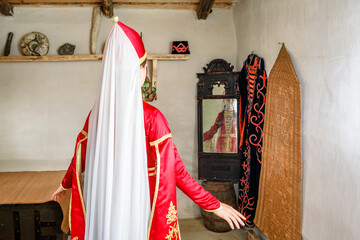 A girl in a bright red national dress is sitting waiting for the groom in the room of a traditional holiday in an old room the peoples of the Caucasus Circassians