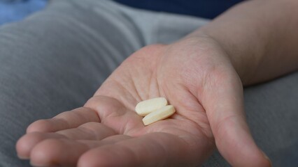 Two yellow tablets are poured on the palm of the hand to treat serious diseases. The patient takes pills that the doctor prescribed to him for the treatment of an infectious disease.