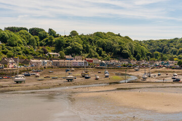 Fototapeta na wymiar Fishguard lower town harbor during low tide with beached fishing and leisure boats on the coast of Pembrokeshire, in Wales, UK
