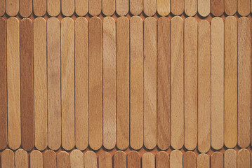 Wooden popsicle sticks, placed in a rows on top of a beige background
