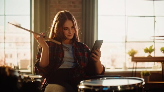 Pretty Drummer Girl Resting Between Her Rock Band Rehearsal. Alternative Stylish Musician Using Her Smartphone, Checking Social Media, Online Fans Community, Chatting with Friends.