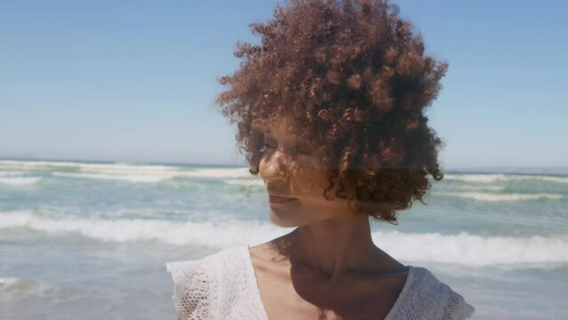 Animation of sea over african american woman smiling