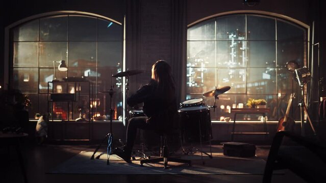 Heavy Metal Drummer Practising a Drum Solo Alone at Night. Female or Male with Long Hair Playing Drums During a Cinematic Evening Jam Session in Stylish Loft Apartment.