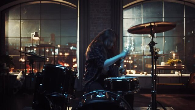 Female Drummer with Long Hair, Nose Piercing and Strong Make-up, Dressed in Dark Jeans and Checkered Flannel Shirt, Playing Drums in a Loft Studio Apartment. Evening or Night Jam Session.