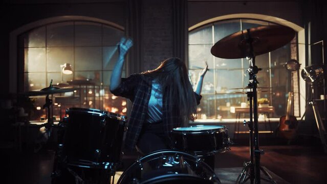 Female Drummer with Long Hair, Nose Piercing and Strong Make-up, Dressed in Dark Jeans and Checkered Flannel Shirt, Playing Drums in a Loft Studio Apartment. Evening or Night Jam Session.