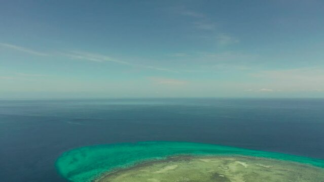 Tropical island in the blue sea with coral reef, top view. Small island with sandy beach. Summer and travel vacation concept, Mantigue island, Philippines, Mindanao
