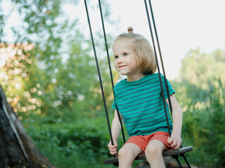 Adorable boy sitting on a swing on a fresh air