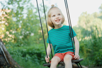 Adorable boy sitting on a swing on a fresh air