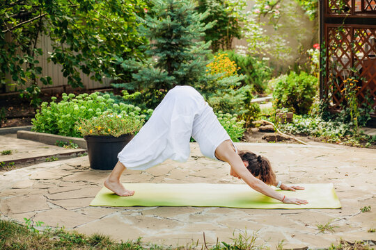 Young woman practices yoga in the garden - Parvatasana, Mountain Pose