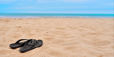 Men's rubber flip-flops stand on beautiful yellow sand. The concept of recreation in hot countries....